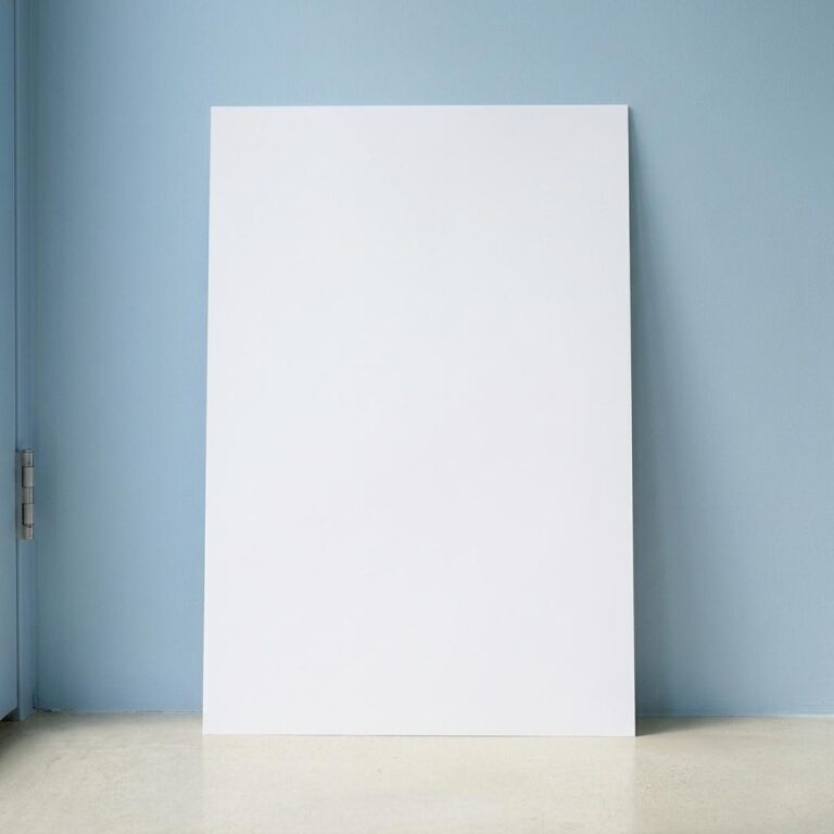 Vertical Poster Mockup Leaning Against a Powder-Blue Wall